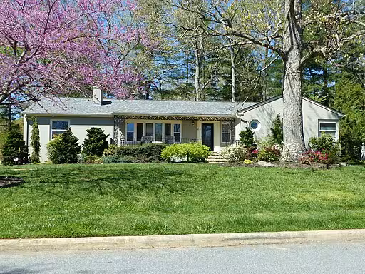 A white colored ranch house with a yard.