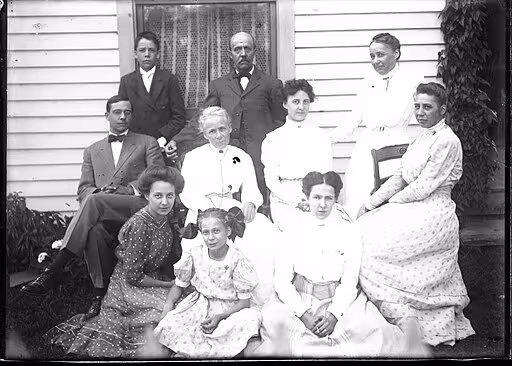 A historic multigenerational family in front of a house.